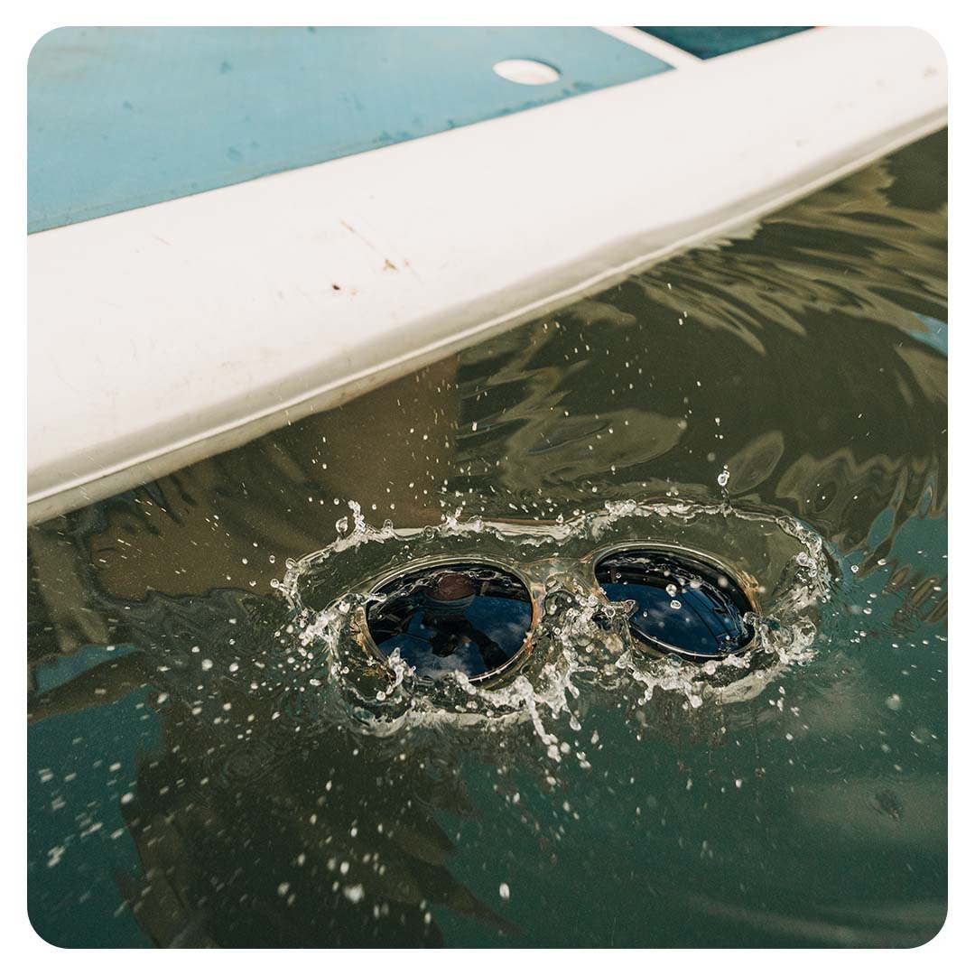 Sunglasses just dropped into the water. A splash of water appears around the floating sunglasses.